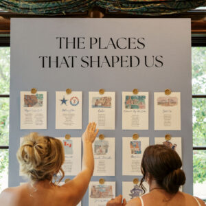 Two brides admiring their custom seating chart rental complete with watercolor details in Dallas, Texas.