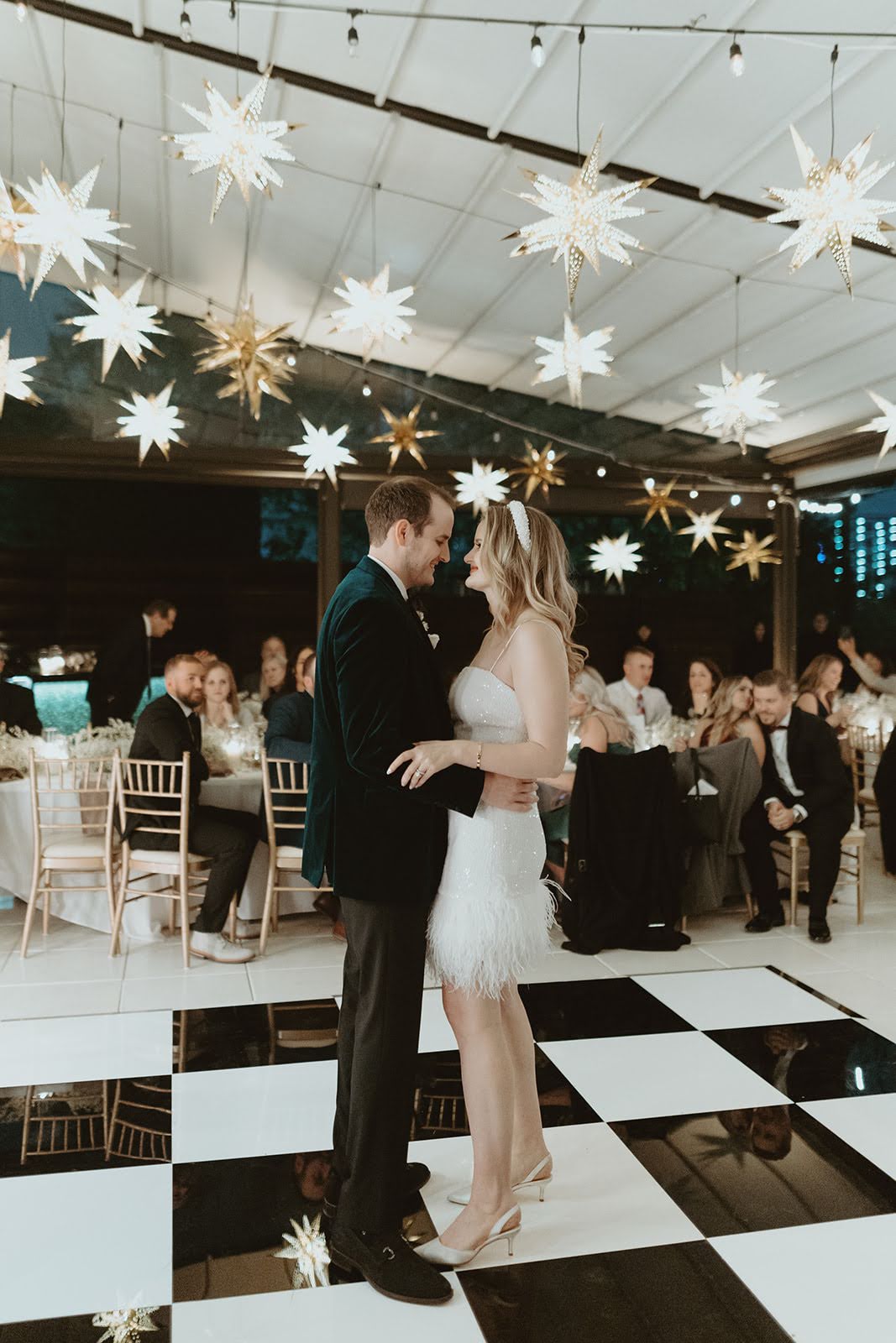 A bride and groom under star lights at their wedding reception.