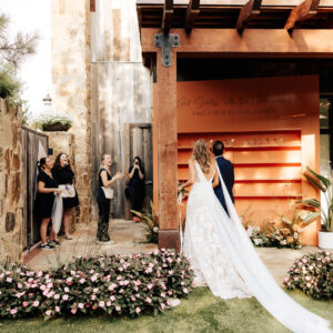A bride and groom walking past their custom cocktail seating chart.