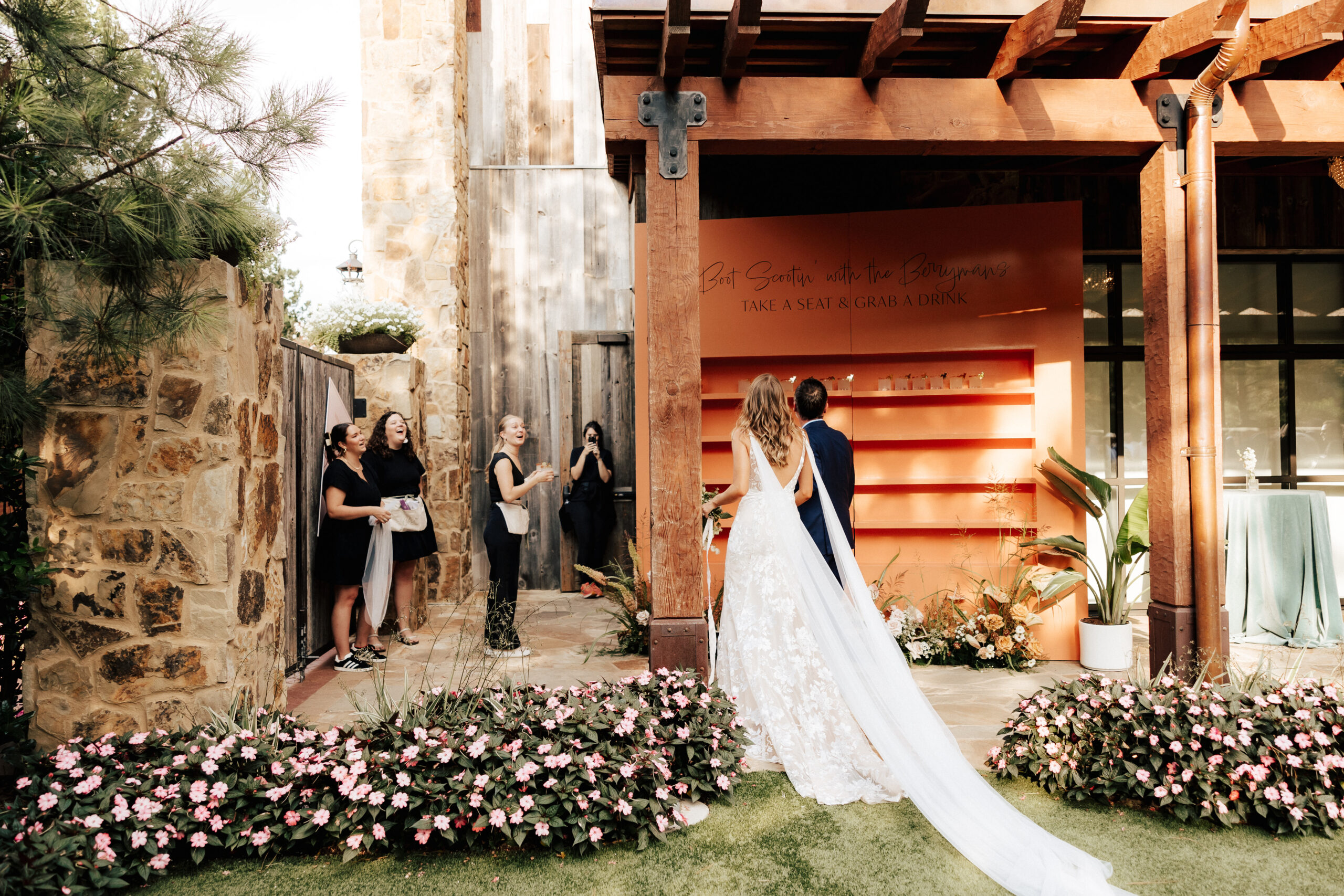 A bride and groom walking past their custom cocktail seating chart.