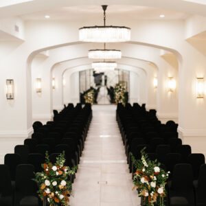 A wedding ceremony site with beautiful chandeliers and black chairs.