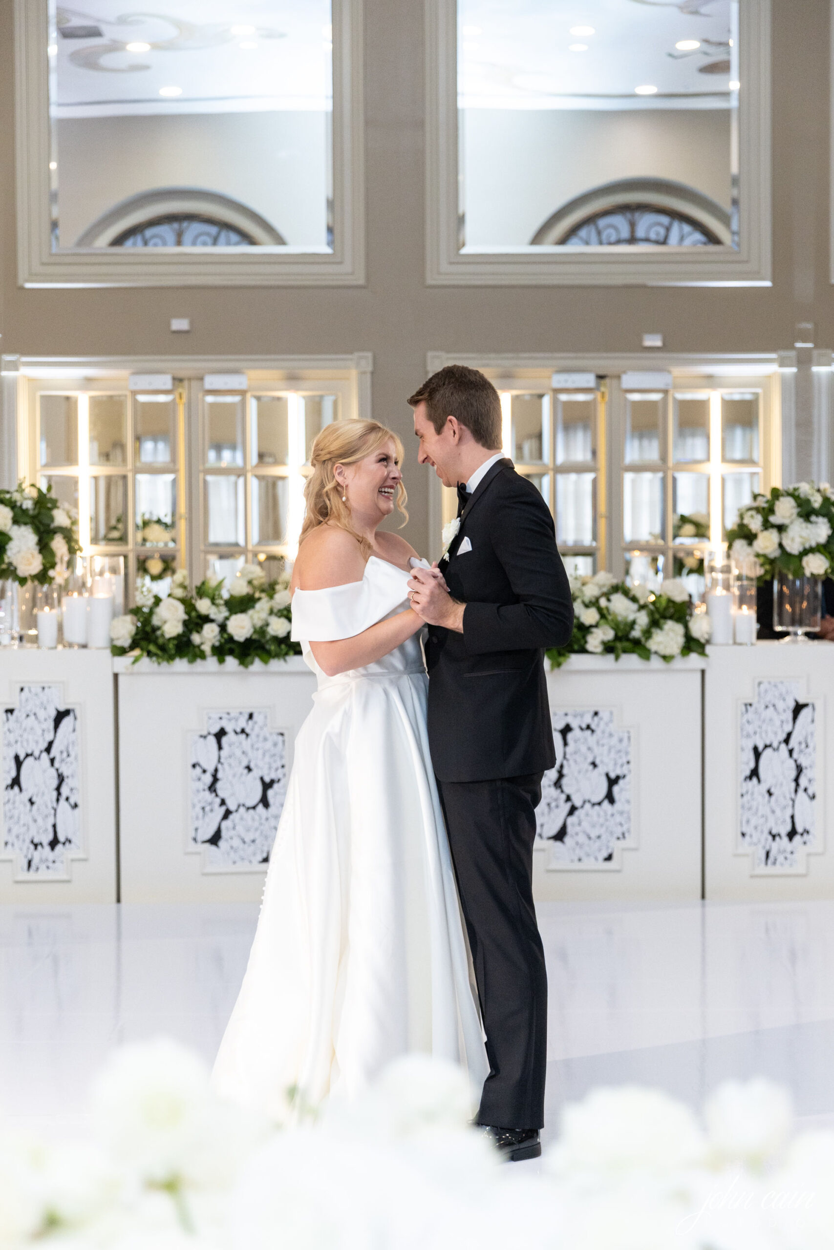 Couple having their first dance in front of their custom stage facade full of flowers.
