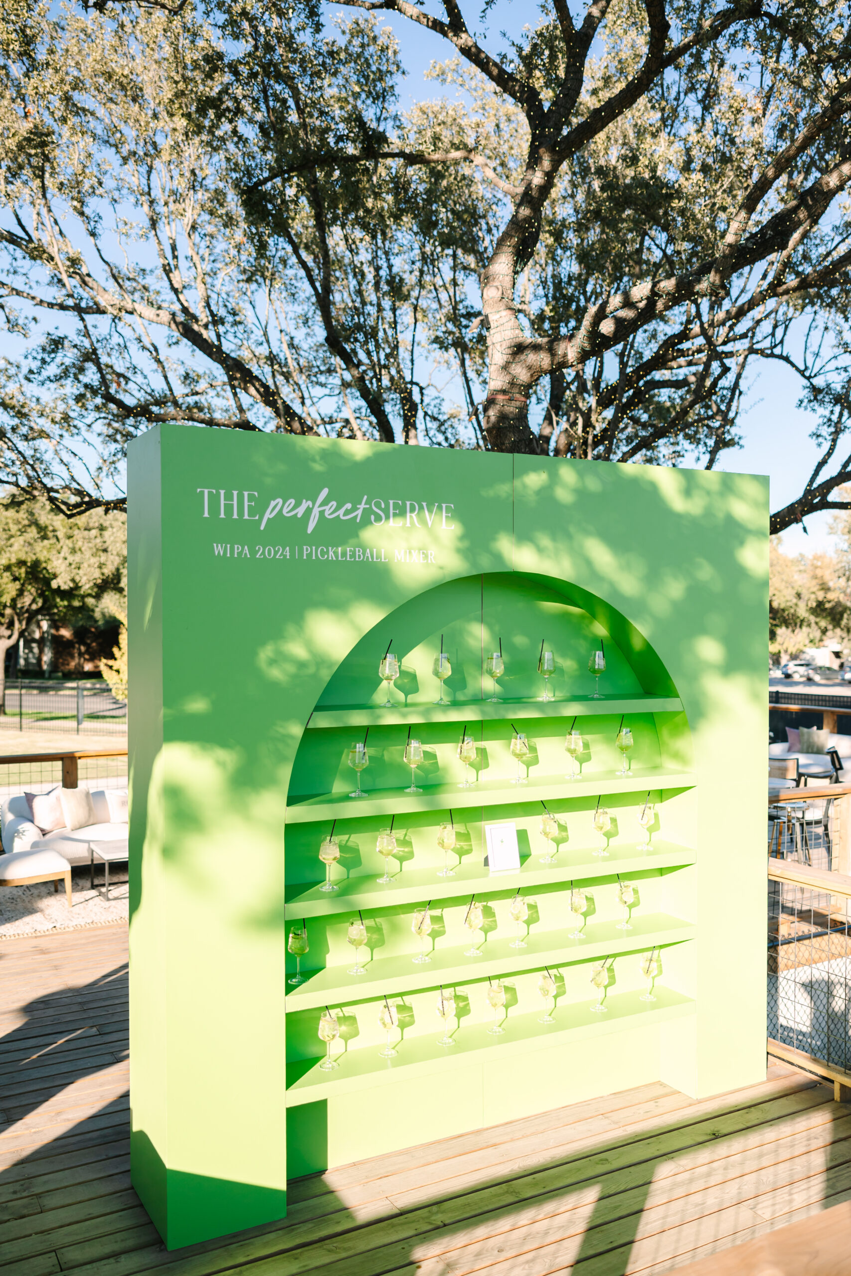 A bright green shelving facade with drinks on each shelf.