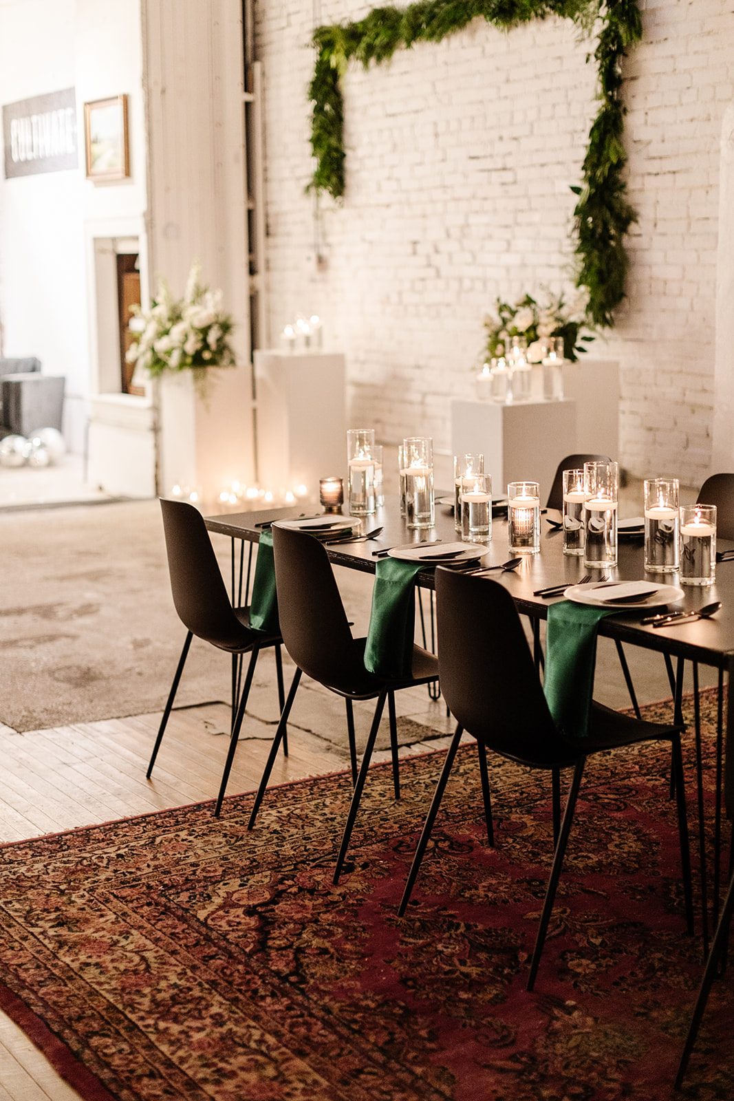 Winter wedding reception with green and black accents and white floral arrangements.